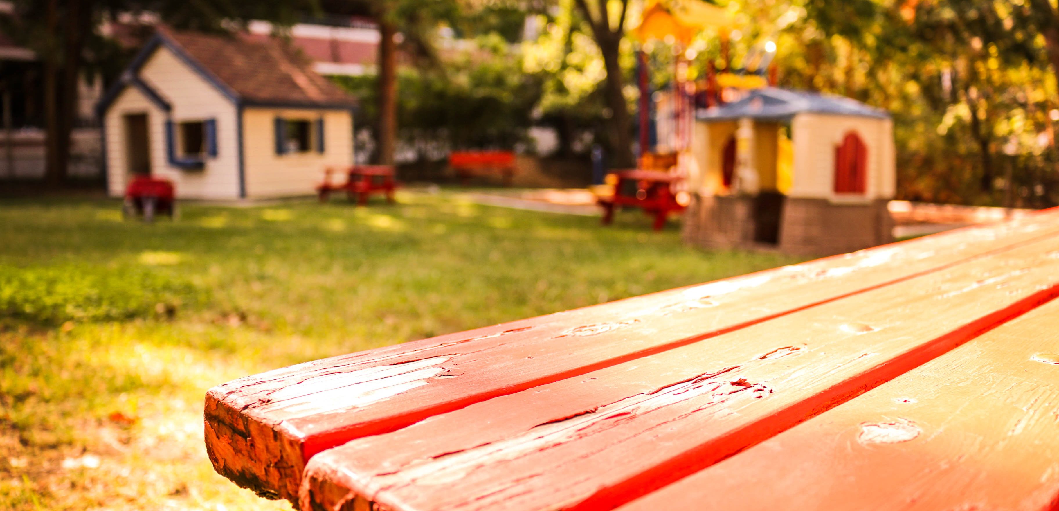 Picture of a backyard with a bench, two playhouses, and play structure